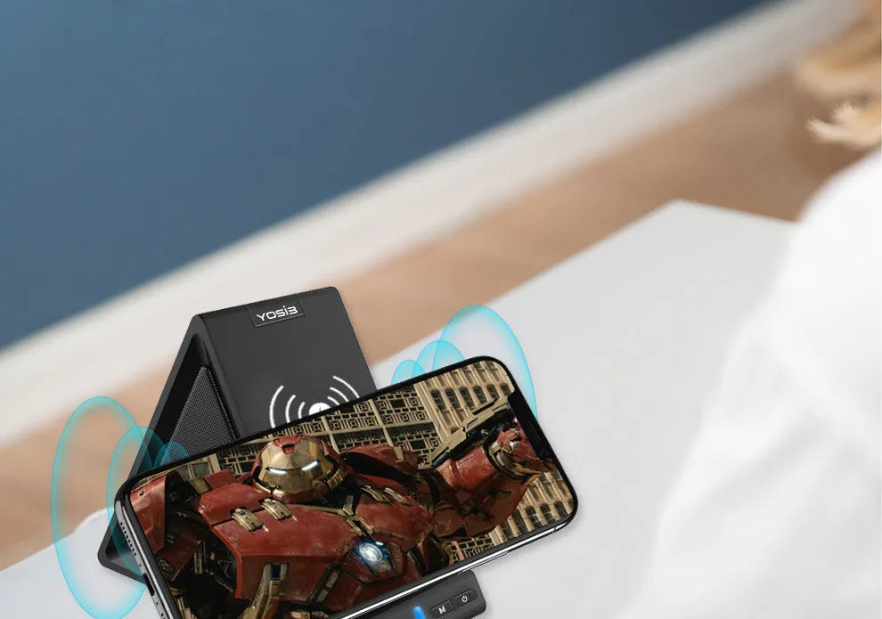 Matte black Bluetooth speaker with integrated phone stand and wireless charging pad on top.