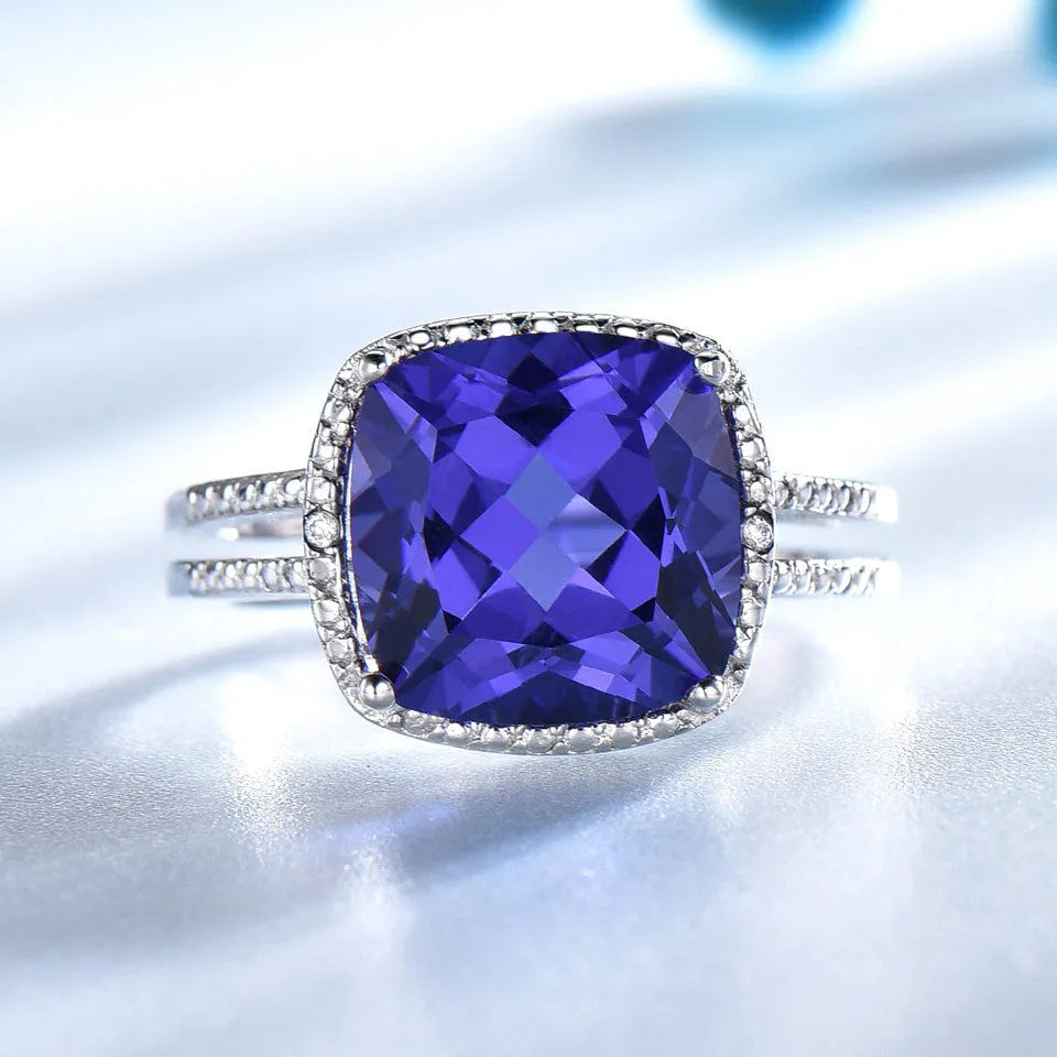Blue tanzanite stone set in a sterling silver women's ring on a grey background.