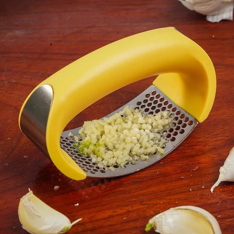 Stainless steel garlic press with ergonomic handle in assorted colours on a kitchen counter.