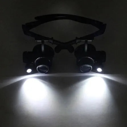 Black double eye magnifying glasses with LED lights and interchangeable lenses on a headband.