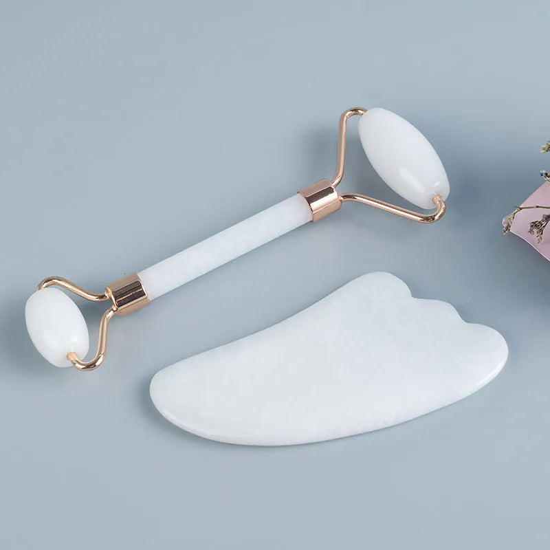 White jade double-headed roller and matching scraping board set on a flat surface.