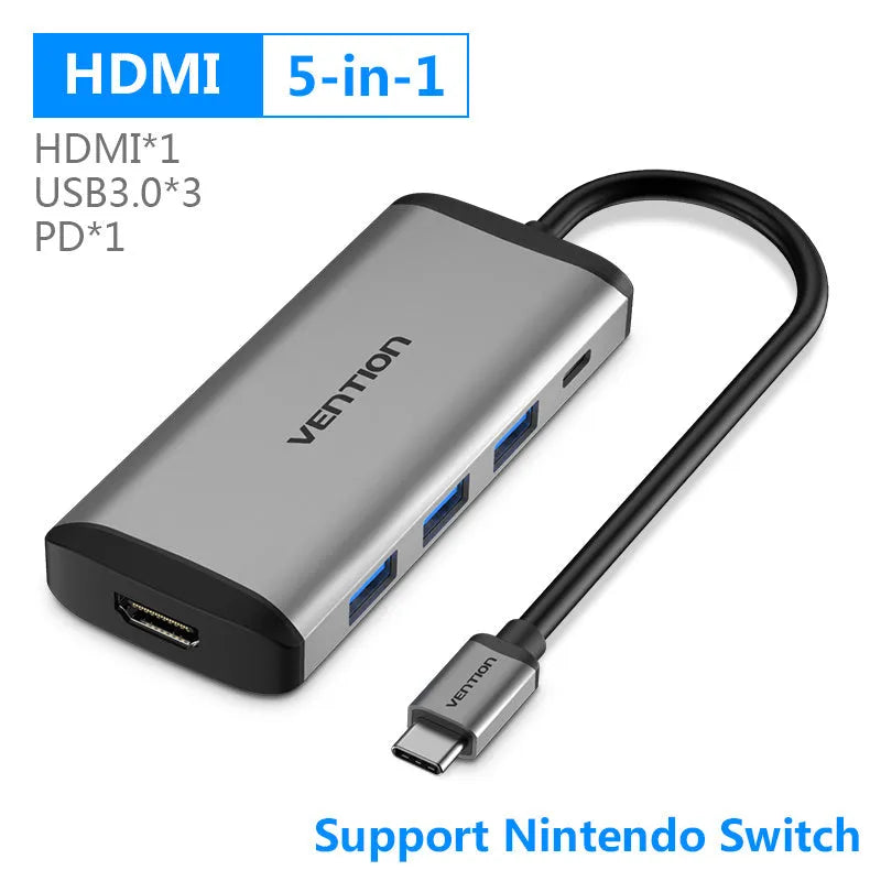 Deep grey aluminium alloy USB-C to HDMI, Ethernet, USB 3.0, and card reader hub adapter on a desk.