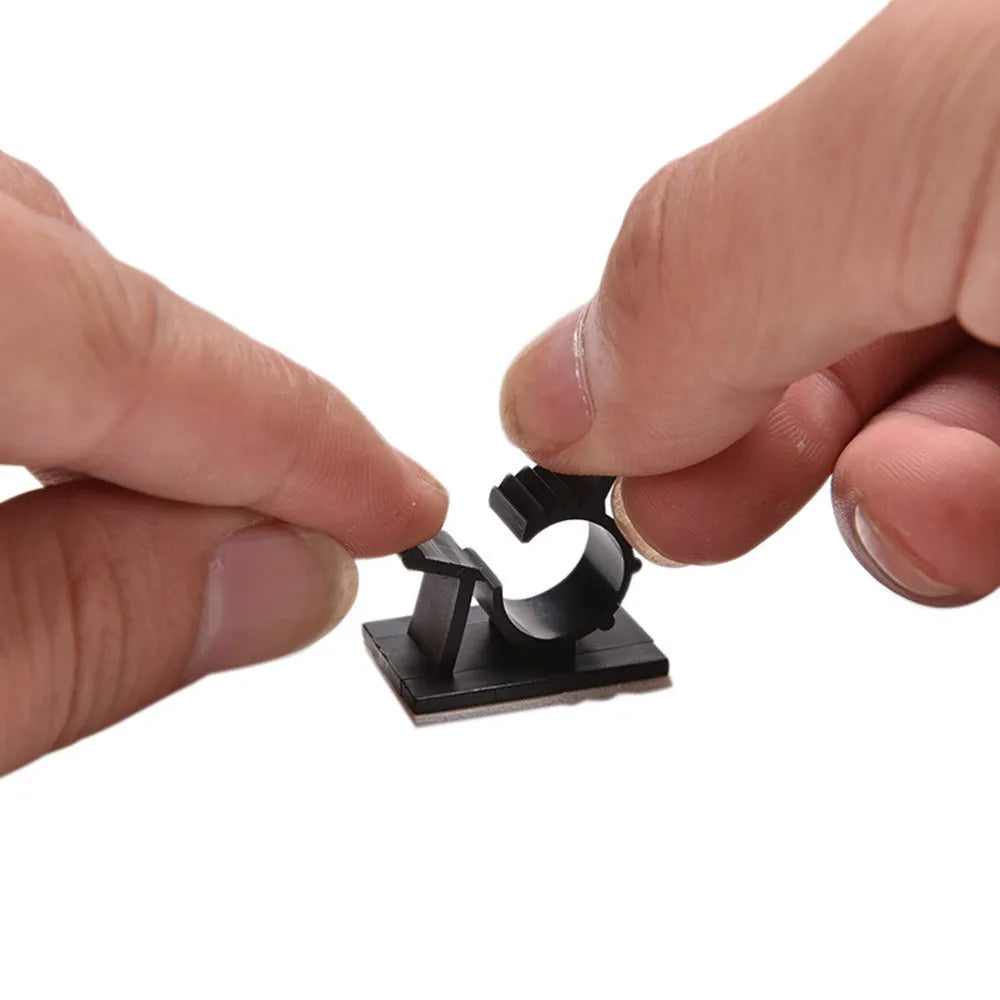 Ten black nylon adhesive cable clamps for wire management, shown with a cable inserted.