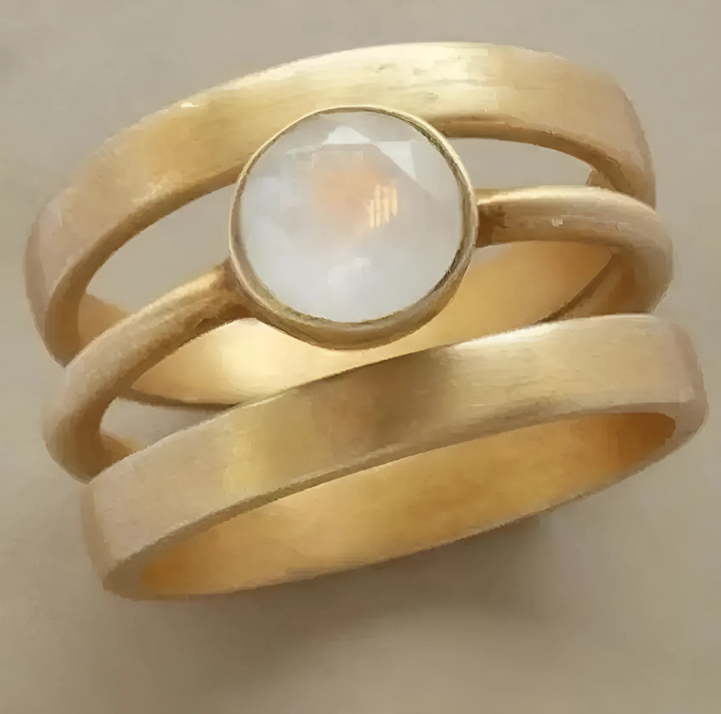 A gold-plated geometric ring with a hollow design and micro-inlaid white chalcedony details.