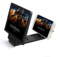 Black folding aluminium mobile phone stand with integrated 3D screen amplifier on a table.