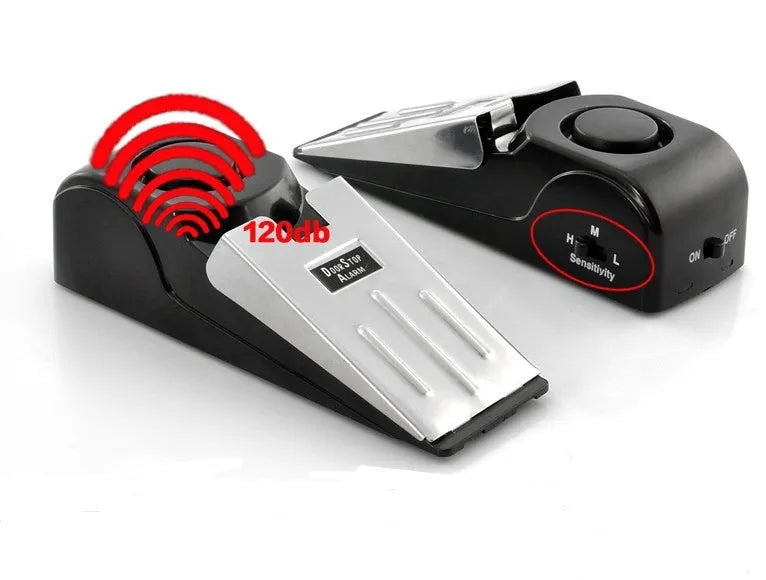 Black portable wedge door alarm with stainless steel cover placed against a hinged door.