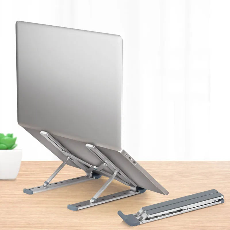 Folding laptop stand in silver with adjustable angle, holding a laptop, showing hollow bottom and non-slip silicone pads