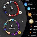 Twelve zodiac bracelets with natural stone beads and metal charms on a silk cord, showing adjustable knot.