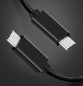 Black USB-C to USB-C cable with stainless steel plug, shown coiled, for 100W charging and 4K video.