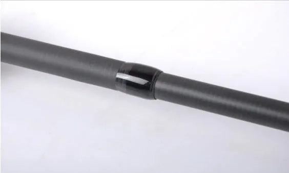 Telescopic carbon fishing rod with matte coating and reel seat on a lakeside bank