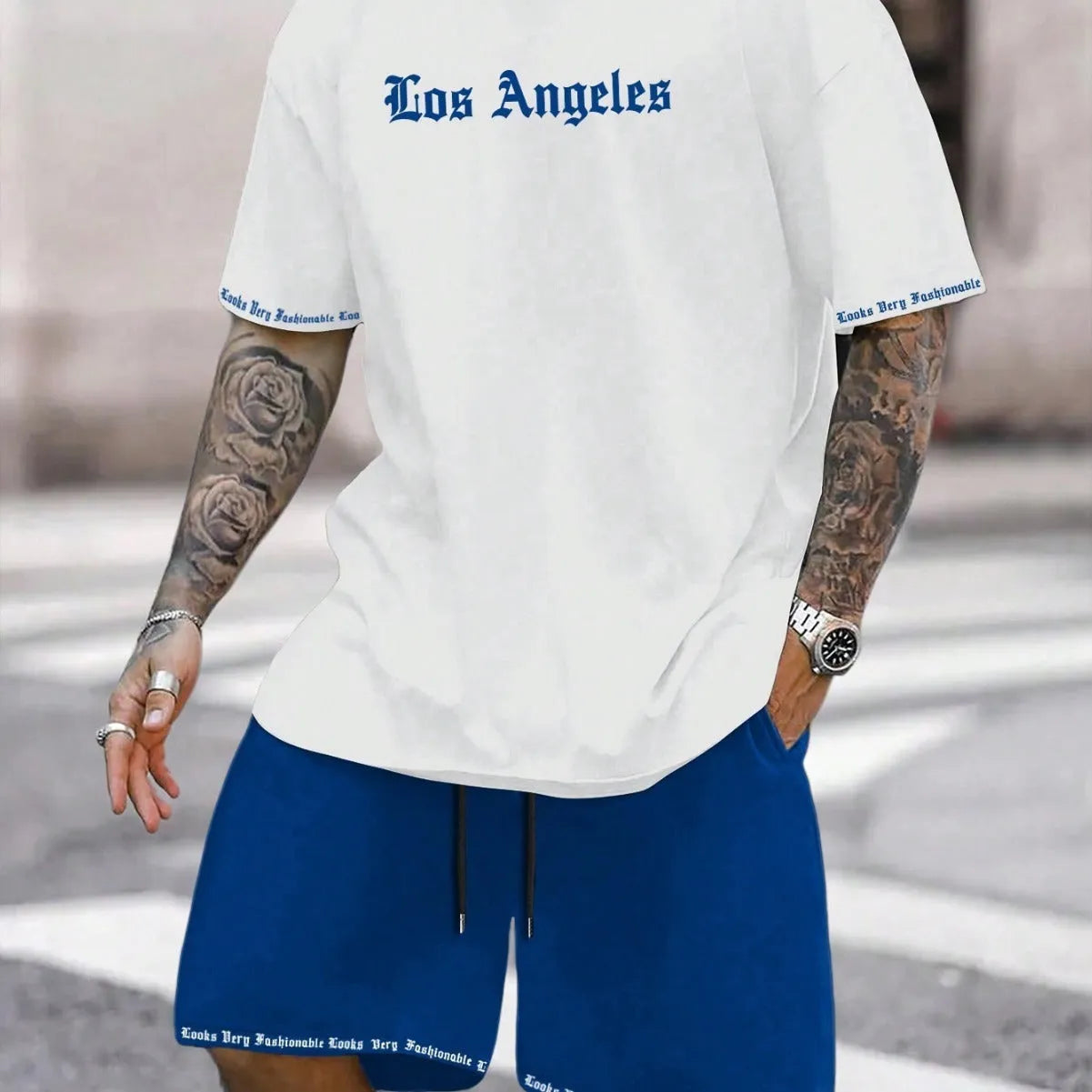 Man wearing a blue short-sleeved top and matching shorts from a sports style suit set.