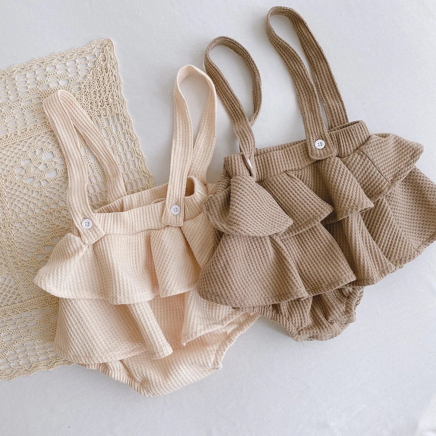 Baby girl wearing a cotton pleated skirt romper with lotus leaf sling design in apricot colour