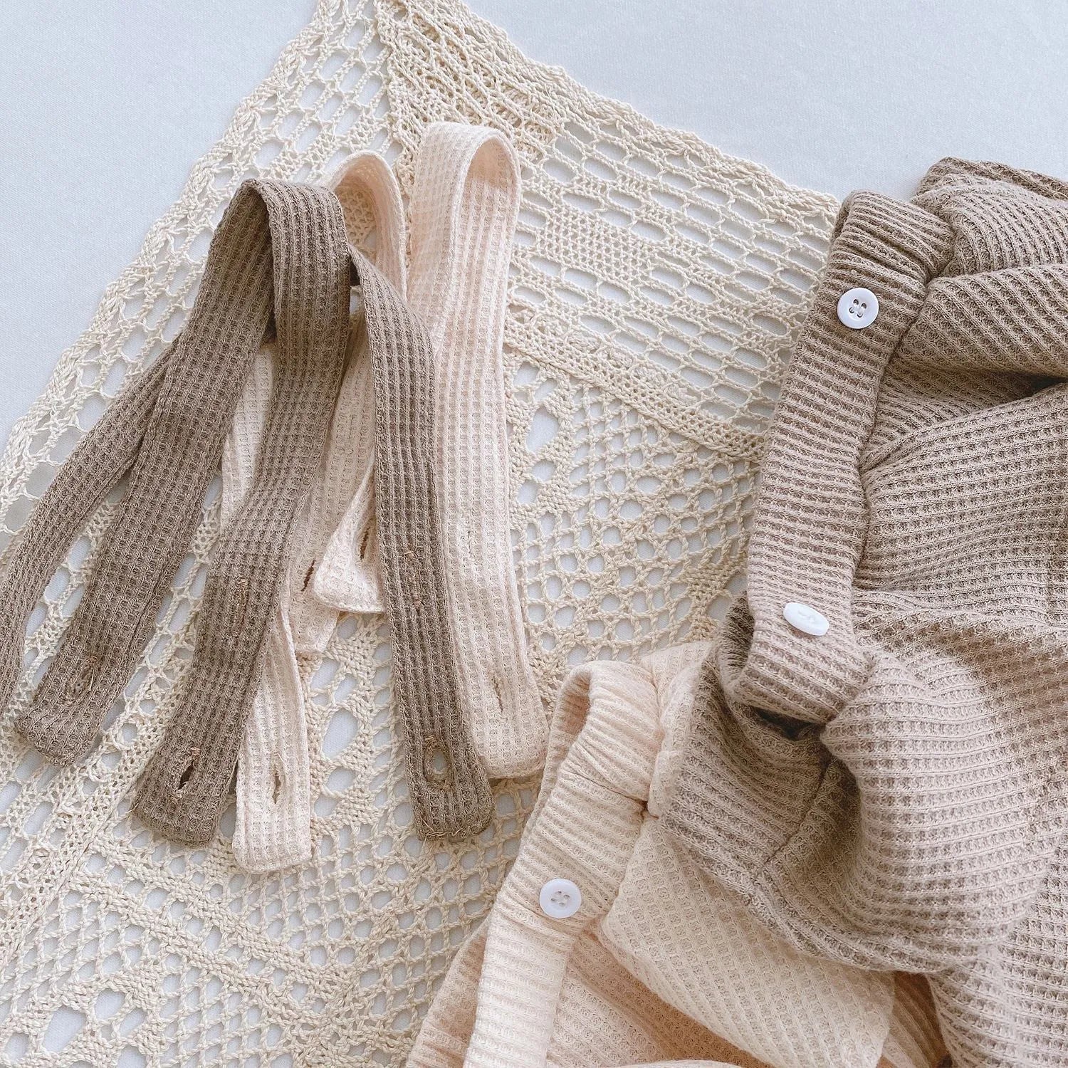 Baby girl wearing a cotton pleated skirt romper with lotus leaf sling design in apricot colour