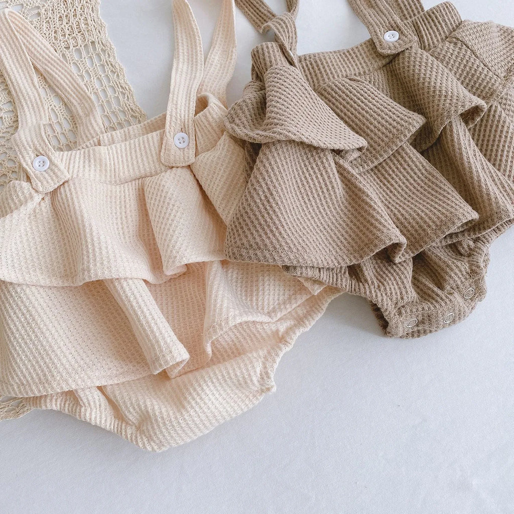 Baby girl wearing a cotton pleated skirt romper with lotus leaf sling design in apricot colour
