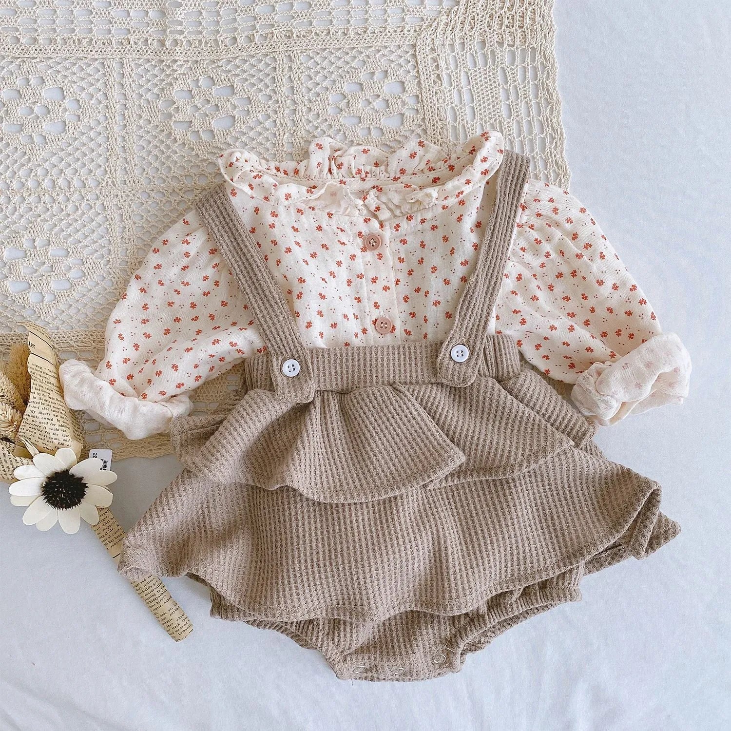 Baby girl wearing a cotton pleated skirt romper with lotus leaf sling design in apricot colour