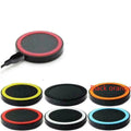 Square Qi wireless charging pad on a table next to a mobile phone.