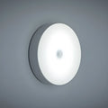 Small circular white USB-rechargeable motion sensing LED night light with adhesive backing.