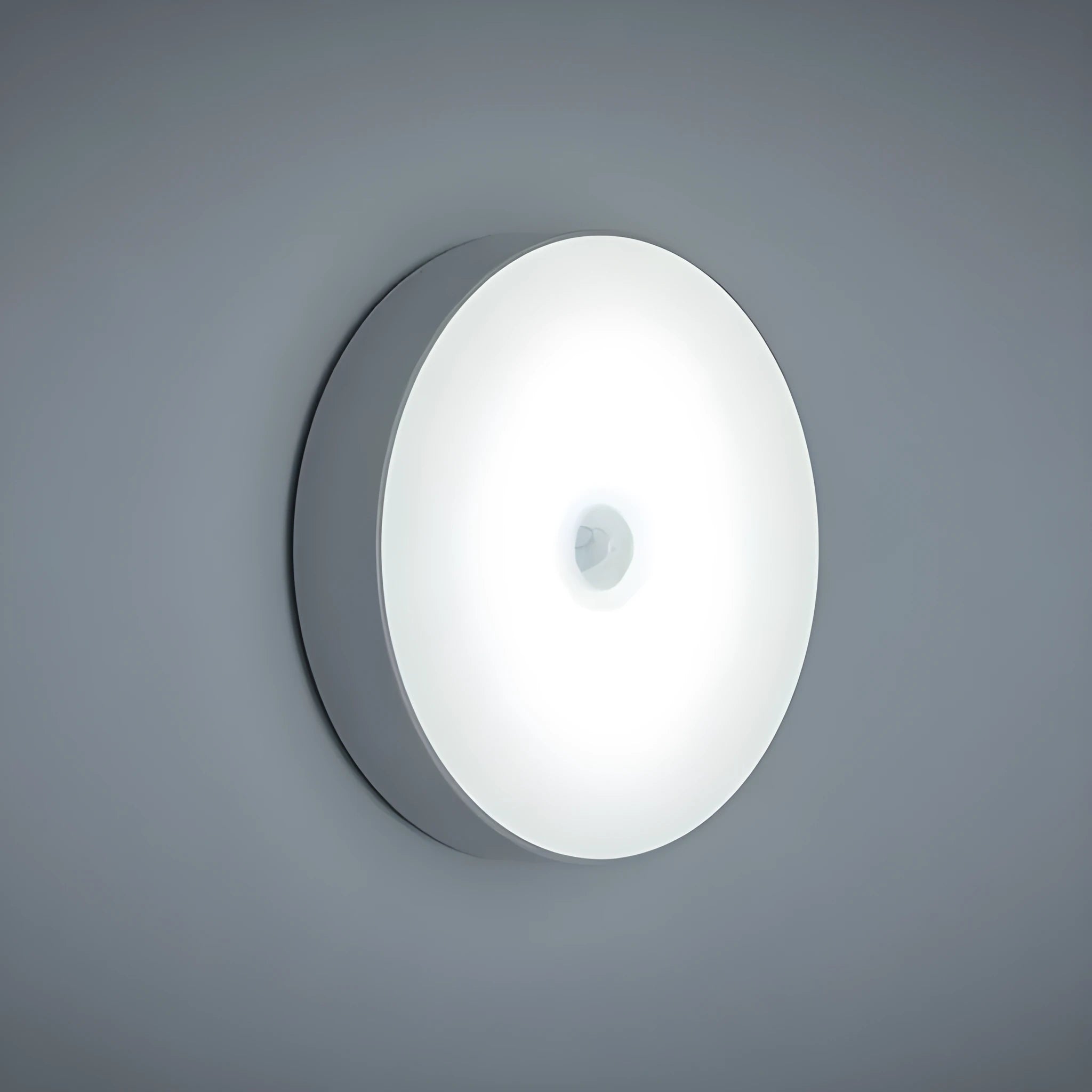 Small circular white USB-rechargeable motion sensing LED night light with adhesive backing.