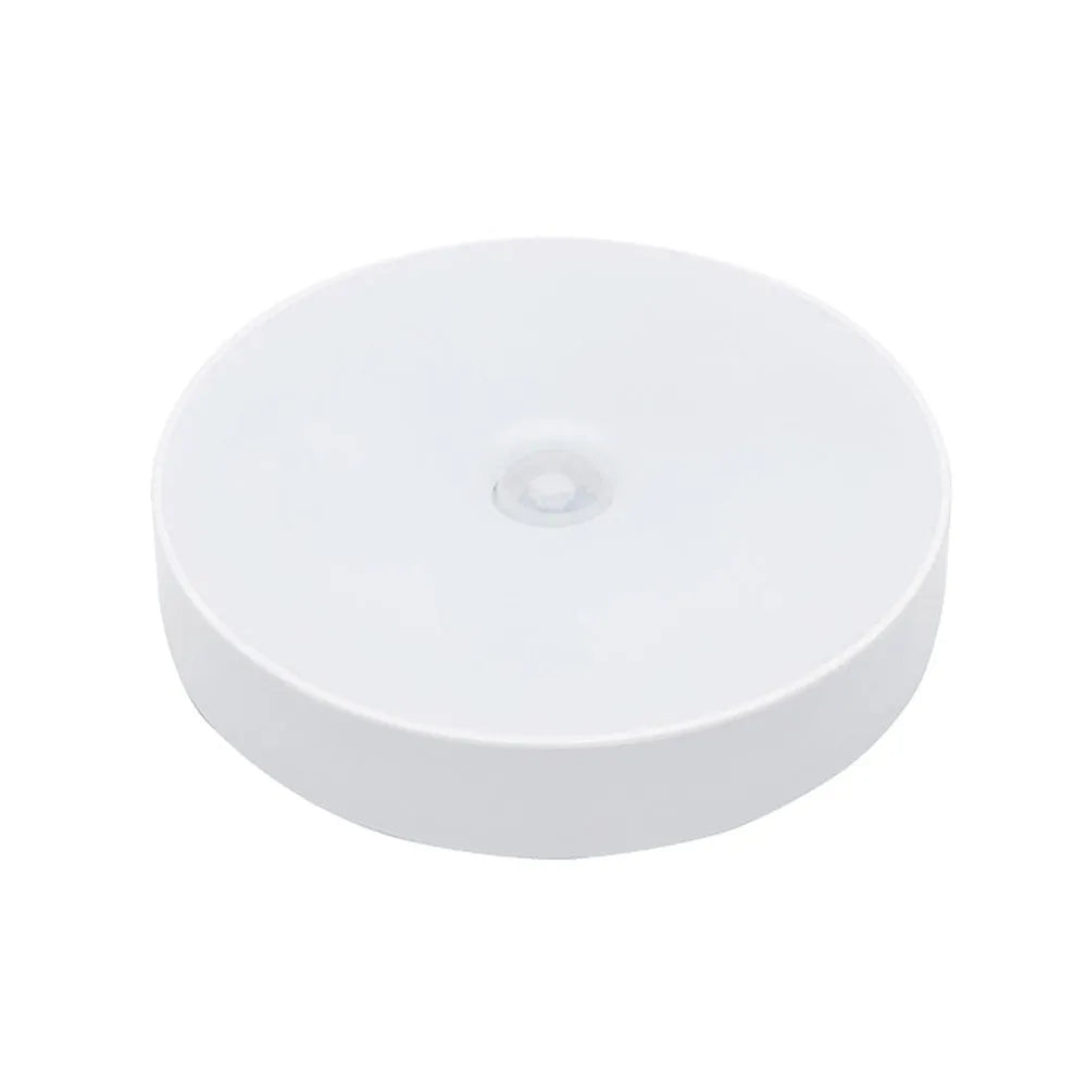 Small circular white USB-rechargeable motion sensing LED night light with adhesive backing.