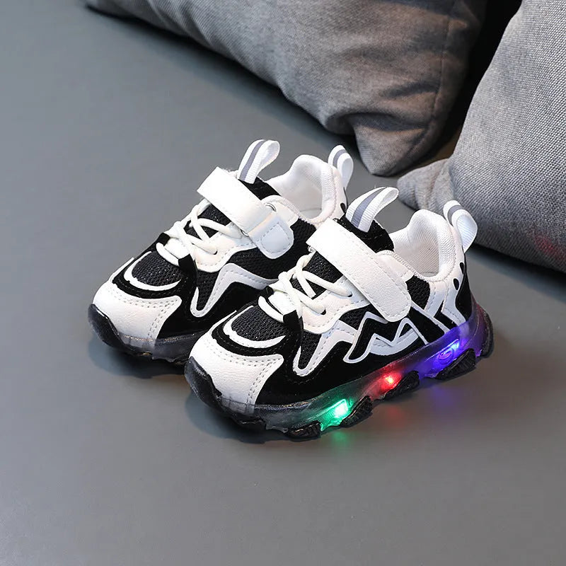 Black children's mesh sneakers with velcro strap and rubber sole on a plain background.