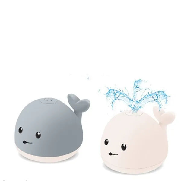 Grey and white cartoon whale bath toy spraying water with LED lights illuminated on water surface.