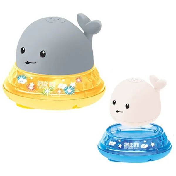 Grey and white cartoon whale bath toy spraying water with LED lights illuminated on water surface.
