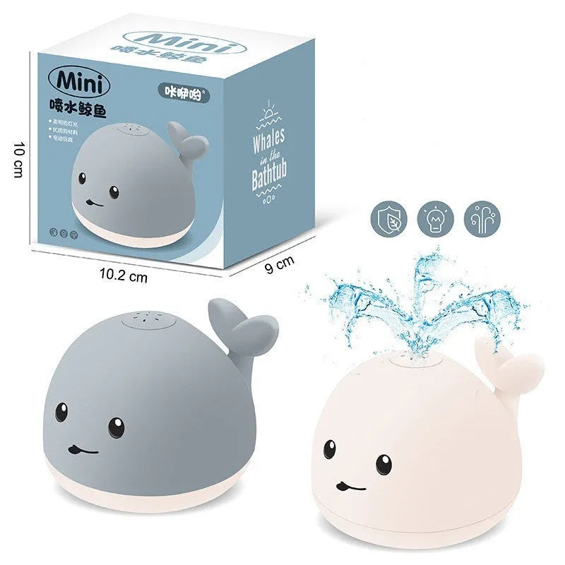 Grey and white cartoon whale bath toy spraying water with LED lights illuminated on water surface.