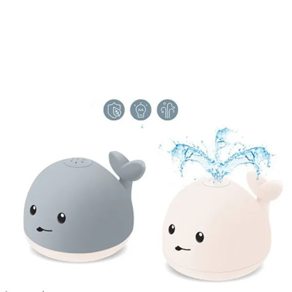 Grey and white cartoon whale bath toy spraying water with LED lights illuminated on water surface.