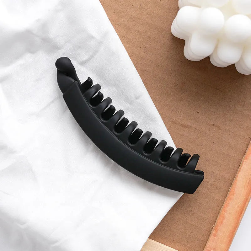 Banana hair clip claw with matte finish in black showing U-shaped design and oversized teeth