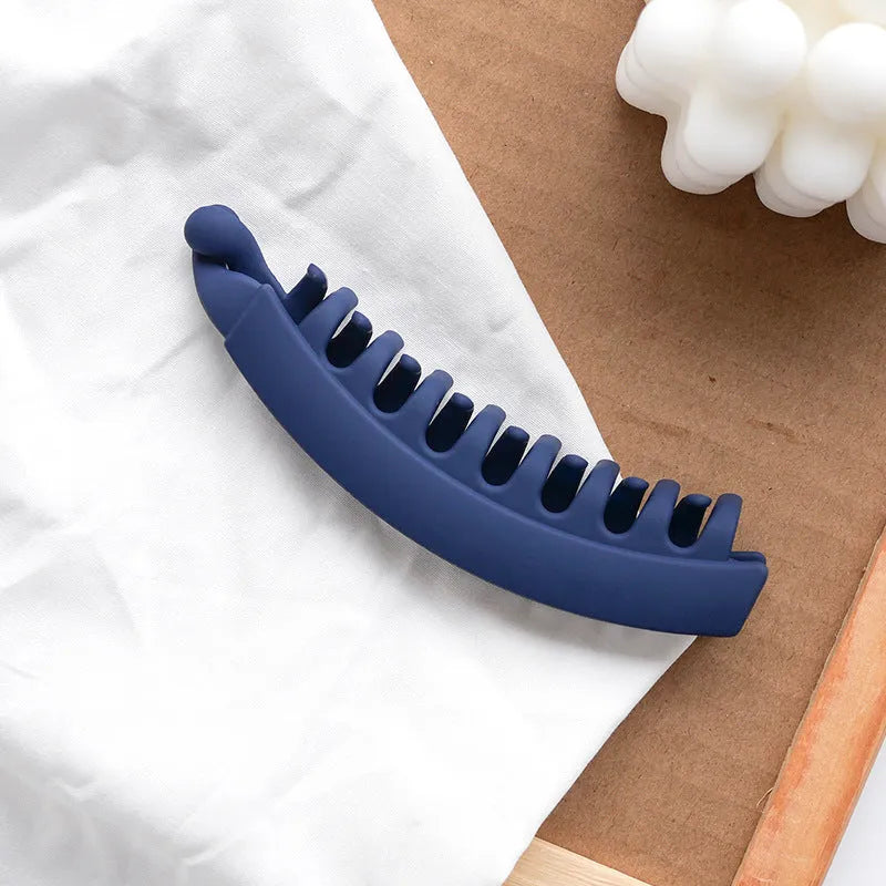 Banana hair clip claw with matte finish in black showing U-shaped design and oversized teeth