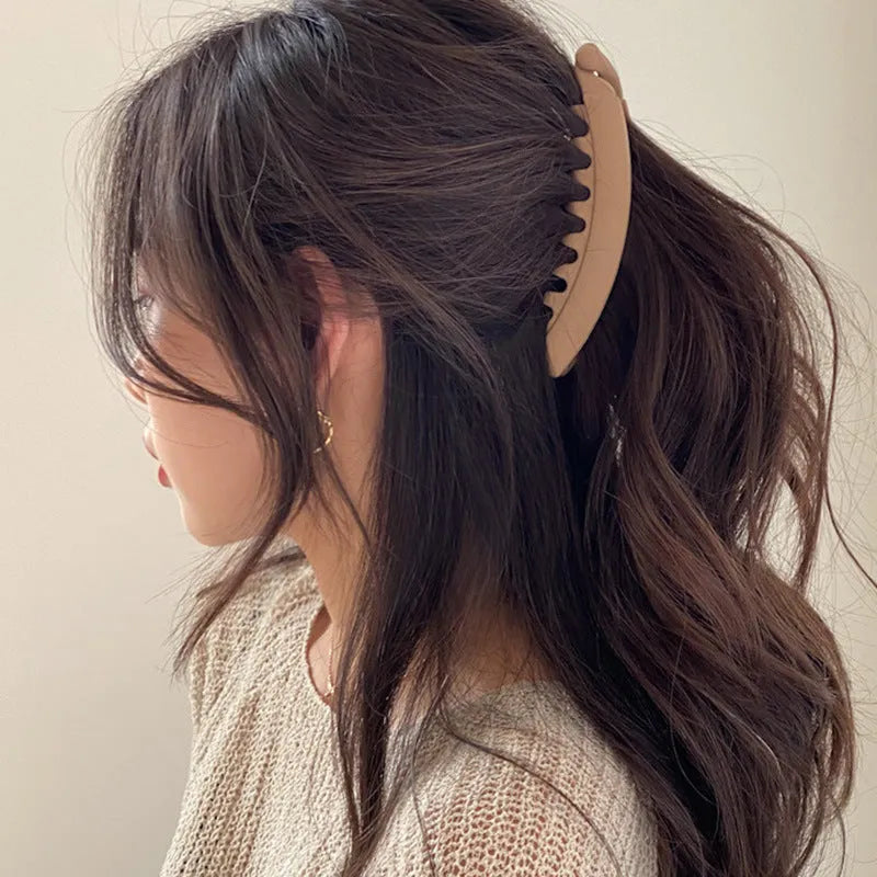 Banana hair clip claw with matte finish in black showing U-shaped design and oversized teeth