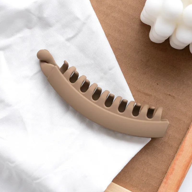 Banana hair clip claw with matte finish in black showing U-shaped design and oversized teeth