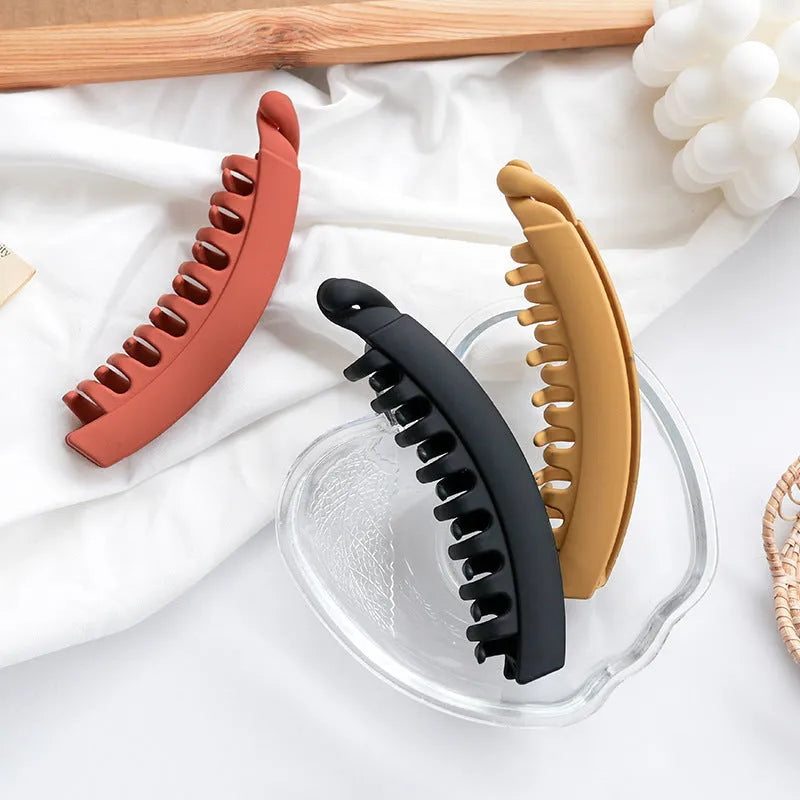 Banana hair clip claw with matte finish in black showing U-shaped design and oversized teeth