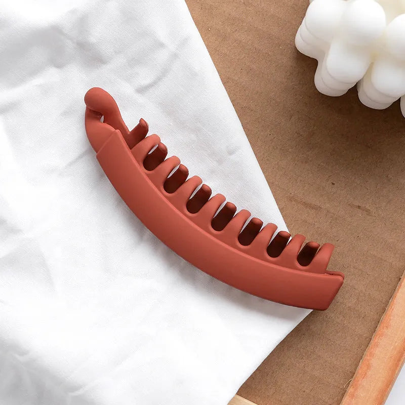 Banana hair clip claw with matte finish in black showing U-shaped design and oversized teeth