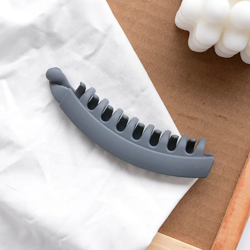 Banana hair clip claw with matte finish in black showing U-shaped design and oversized teeth