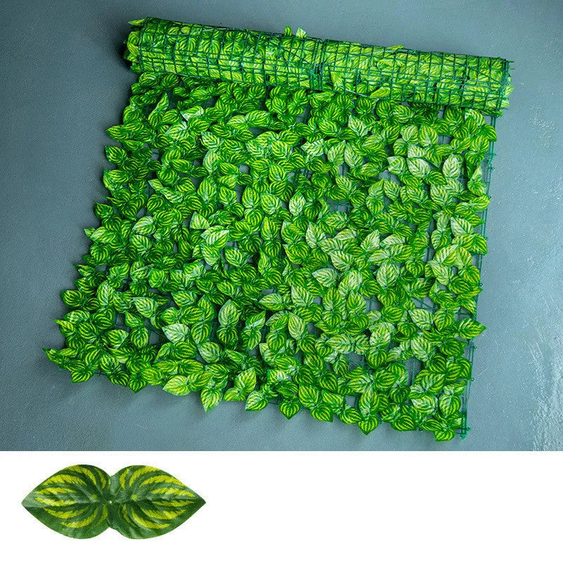 Plastic artificial fence panel with green colour-printed leaf design in a garden setting