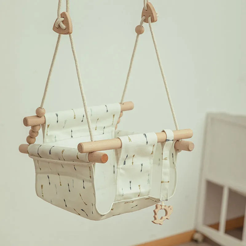 Cotton canvas baby swing chair with wooden frame and cushion, hanging with decorative tassels.