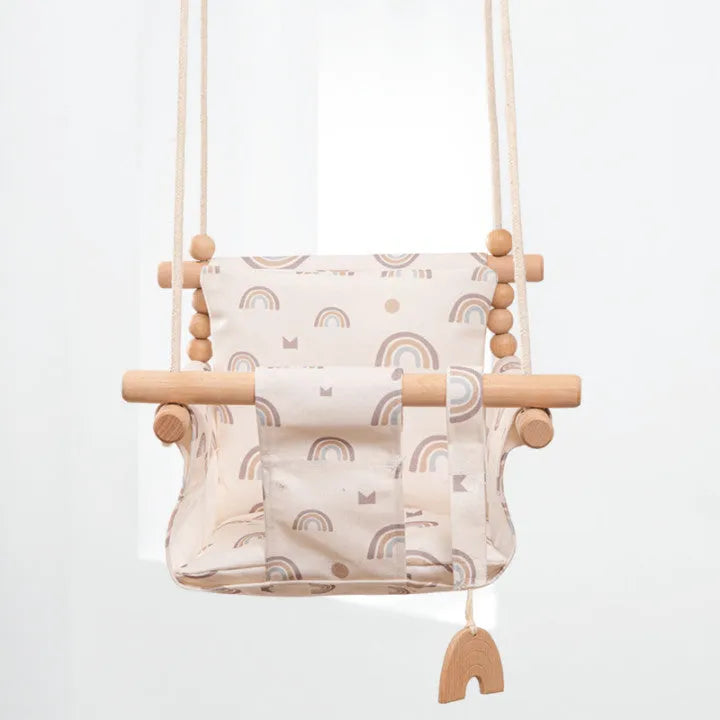 Cotton canvas baby swing chair with wooden frame and cushion, hanging with decorative tassels.
