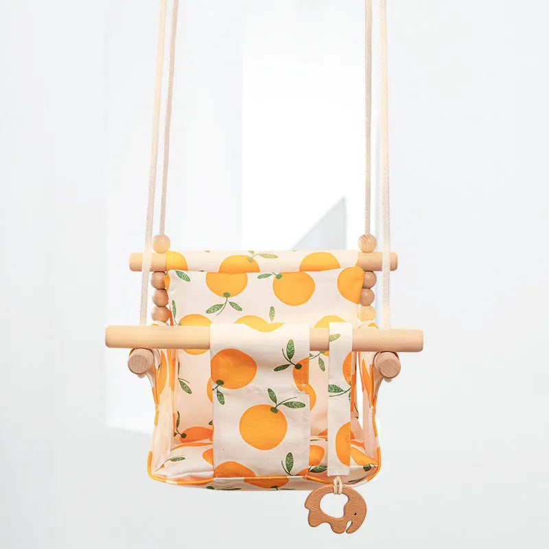 Cotton canvas baby swing chair with wooden frame and cushion, hanging with decorative tassels.