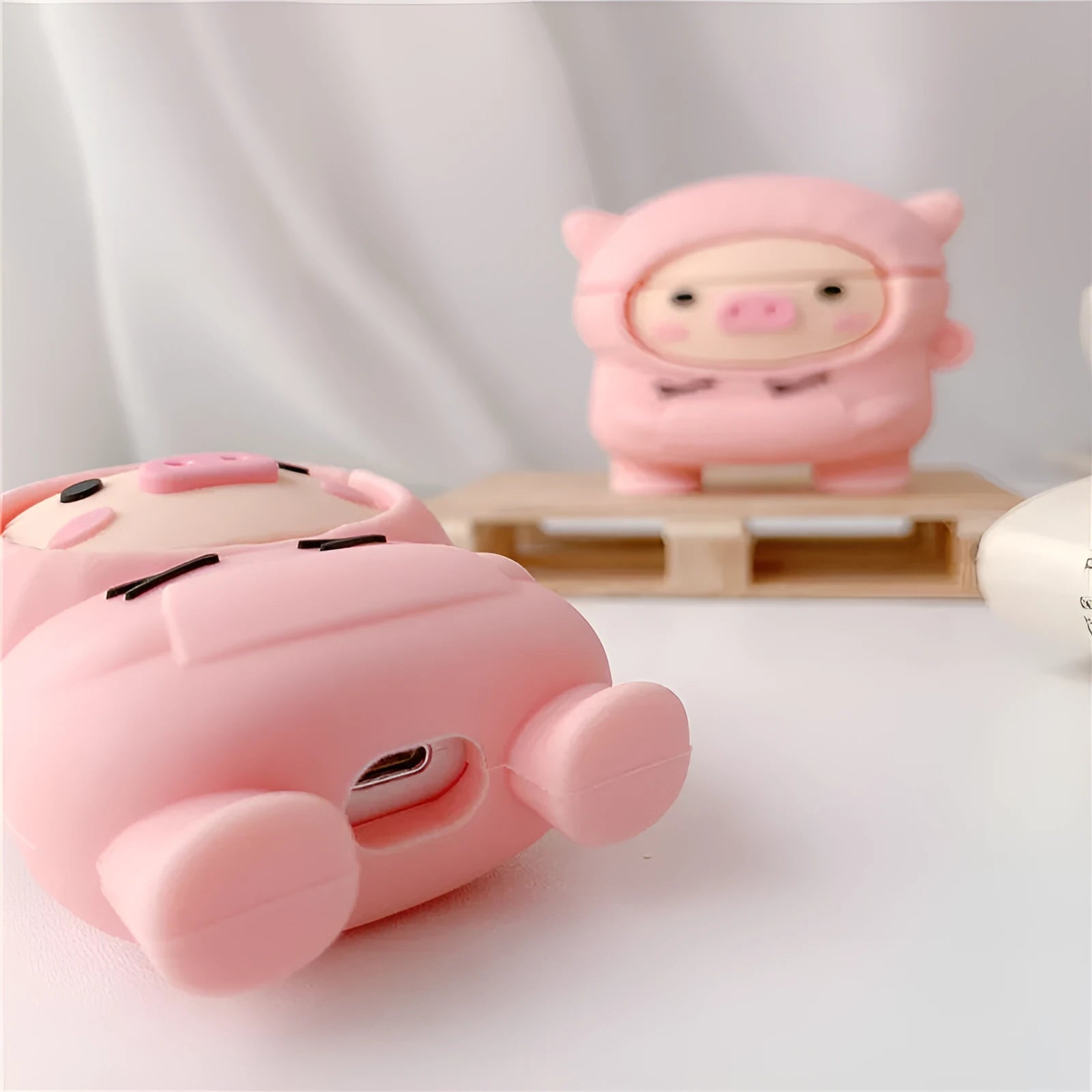 Pink silicone AirPods case cover with cartoon pig design and a metal carry hook.
