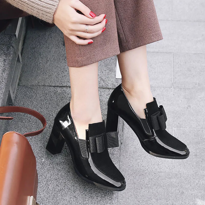Black patent leather women's high heel shoes with a thick heel and square toe on a rubber sole