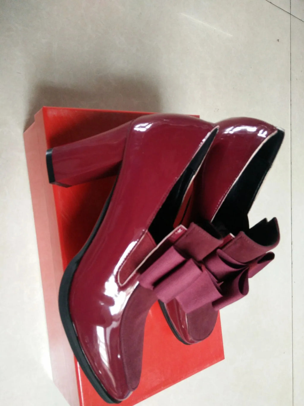 Black patent leather women's high heel shoes with a thick heel and square toe on a rubber sole
