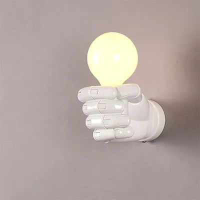 Close-up of a black resin wall lamp shaped like a clenched fist, mounted on a textured wall.