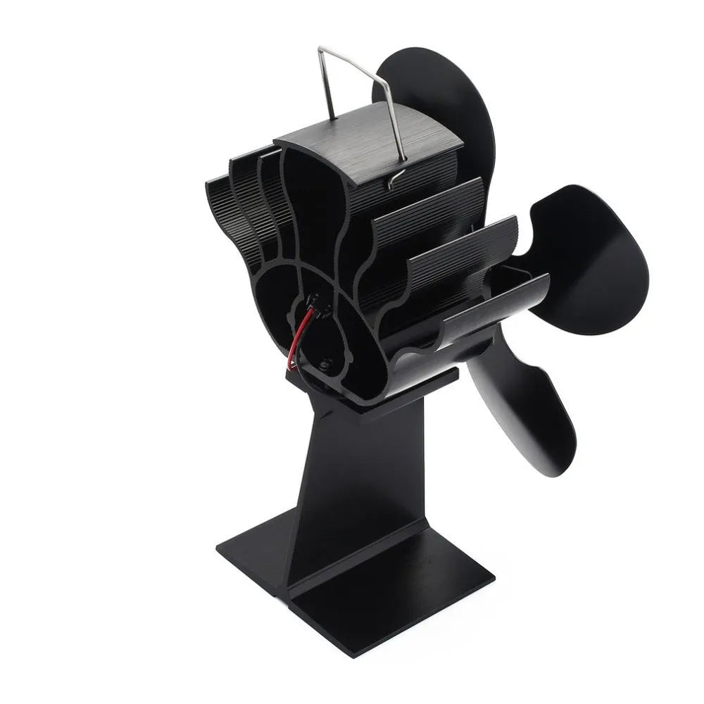 Black Yotsuba style thermodynamic fireplace fan on a fireplace, showing metal blades and compact 17x11.5x25cm size.