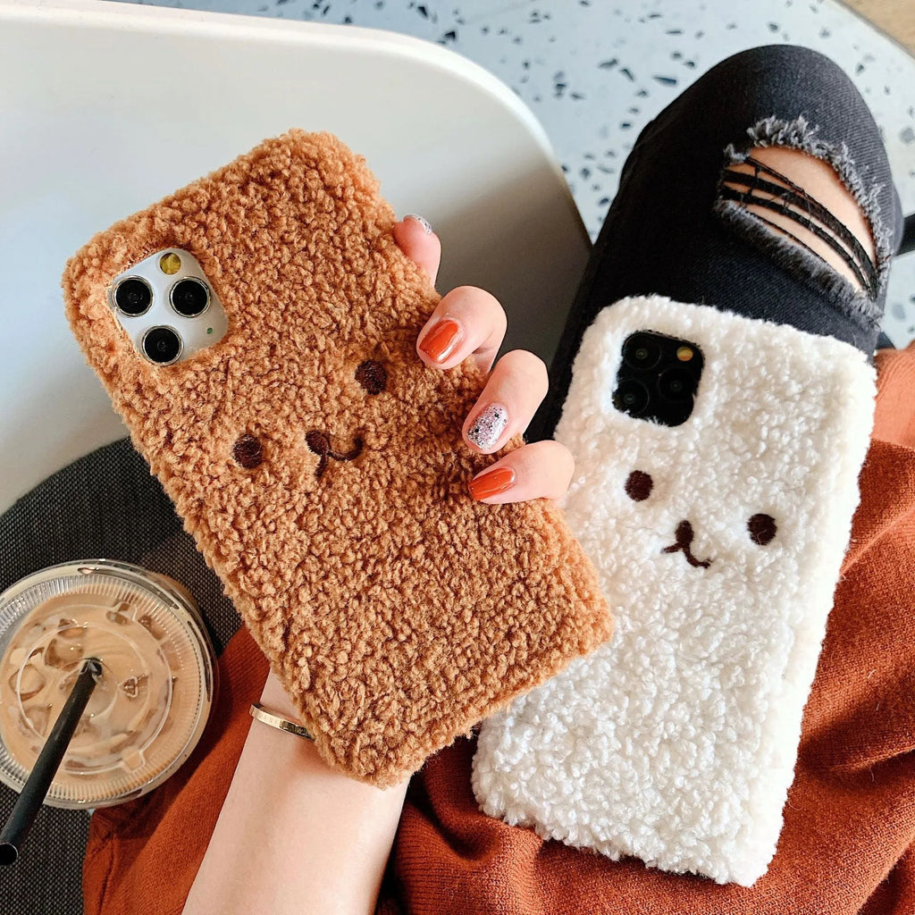Brown embroidered plush bear face on a clear TPU iPhone case, showing precise cutouts for camera and ports.