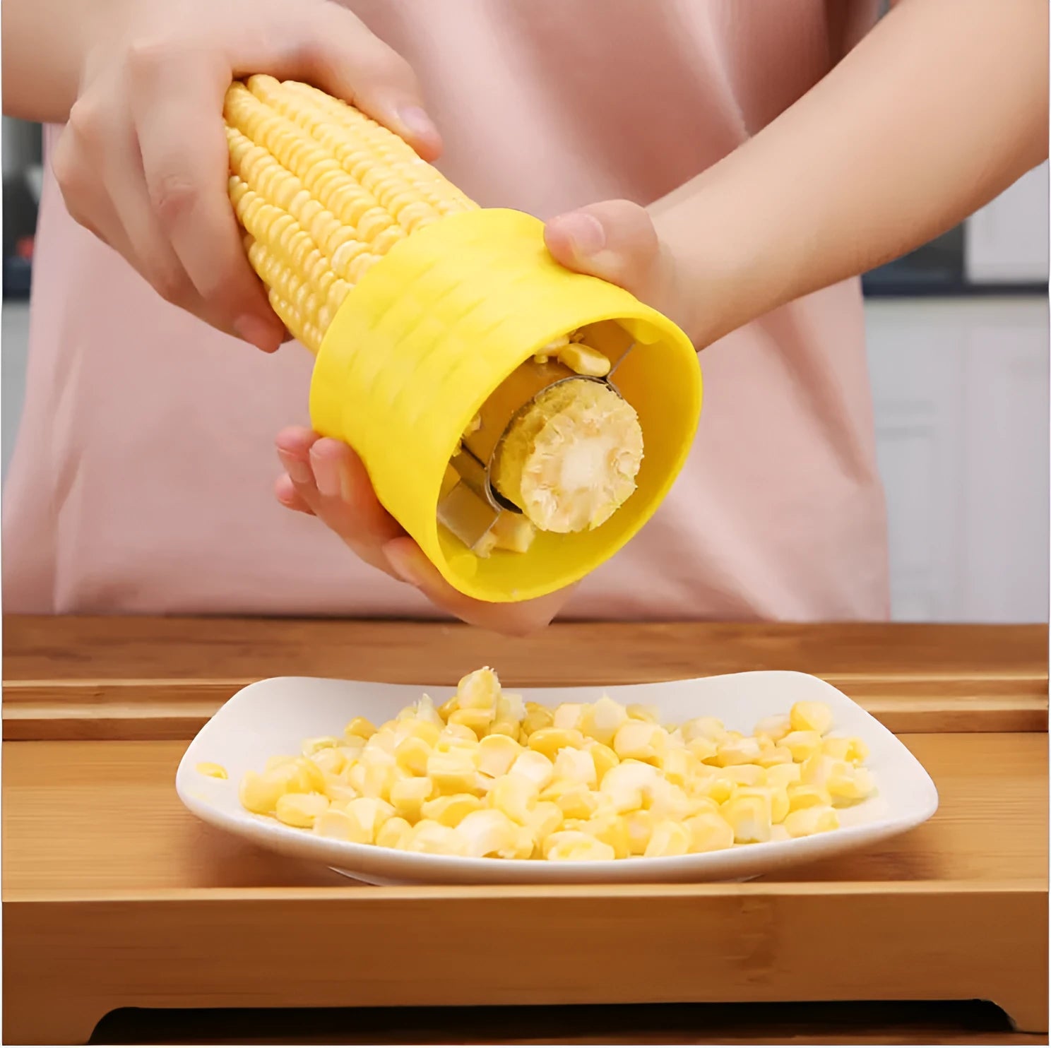 Yellow manual corn thresher kitchen tool with a corn-shaped plastic body and visible stainless steel gear.
