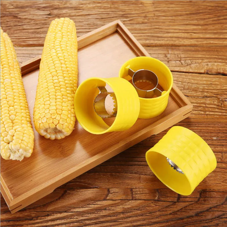 Yellow manual corn thresher kitchen tool with a corn-shaped plastic body and visible stainless steel gear.