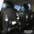 PU leather car seat back organiser with multiple pockets and a detachable bottom waste bin, hanging behind a car headrest.