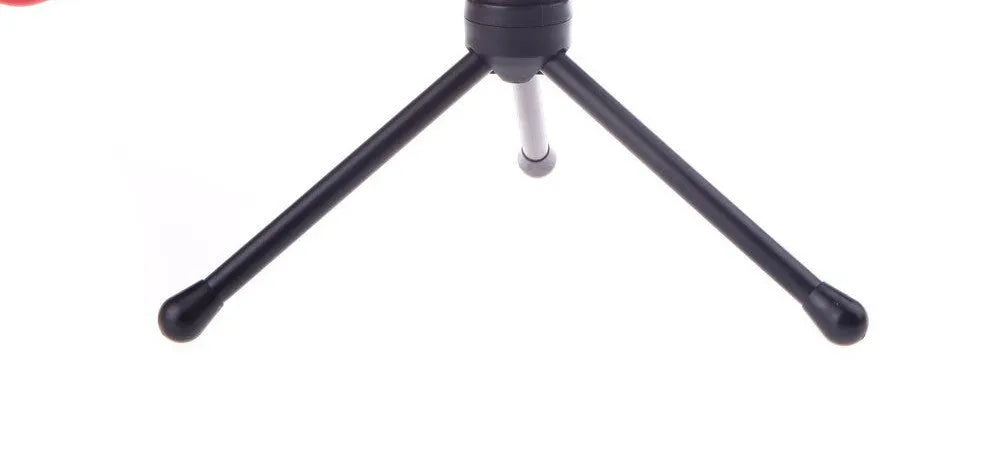 Black mini phone wired microphone with 3.5mm plug and attached adjustable holder clip on a desk.