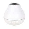 White round Bluetooth humidifier and essential oil diffuser with LED night light on a wooden surface.